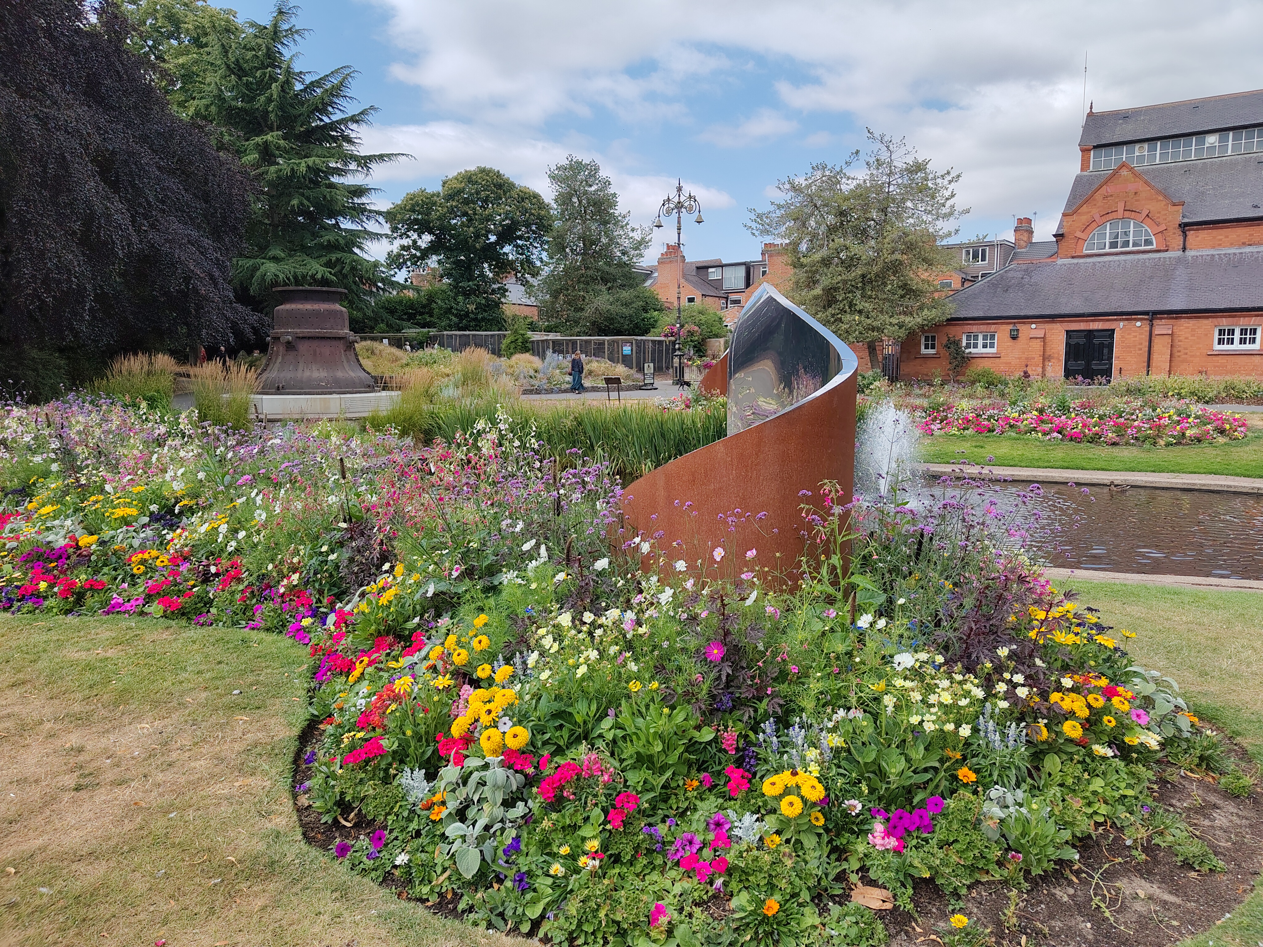 Bell casing in a park. The flowerbeds are full of colourful flowers.